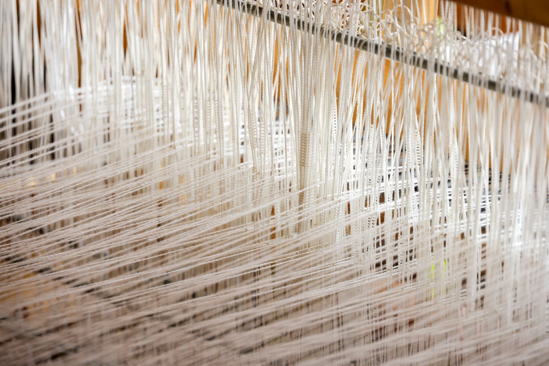 Detailed view of white threads woven on a loom, showcasing intricate textile work.